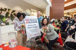 Event attendees hold flowers in front of the "Grow with Ahuja" flower bouquet activity.