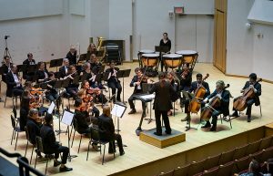Orchestra members and conductor playing onstage