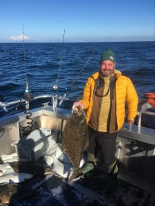 David Downing holding a huge fish he caught in Alaska, while wearing a Packers beanie