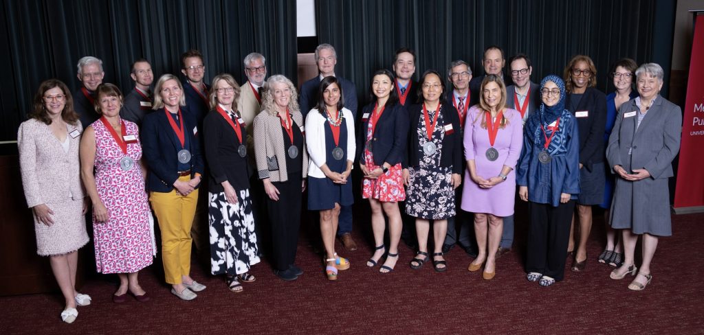 A group of smiling individuals wearing medals around their necks