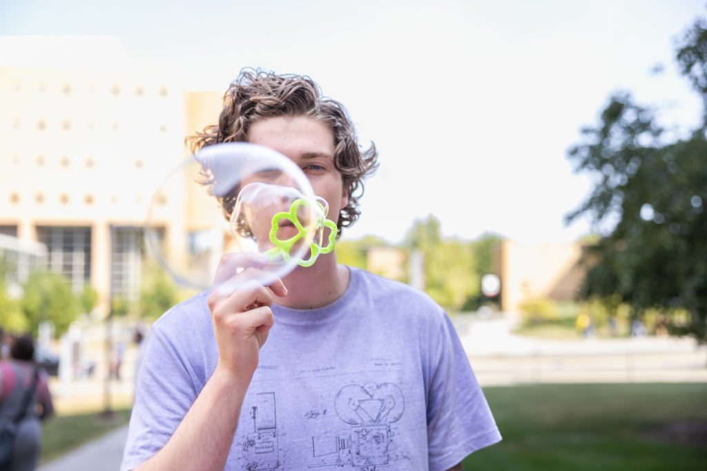 Person blowing bubbles into the camera outside
