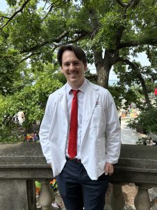 Felix Mannella smiles in a white coat