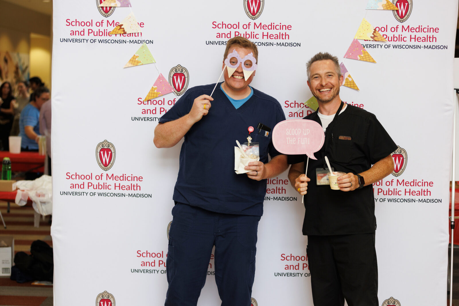 SMPH staff and faculty pose with props and ice cream behind SMPH photo wall.